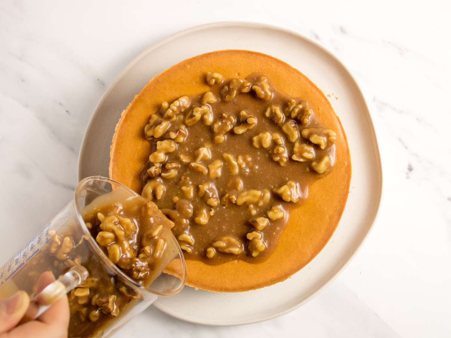 Pouring the walnut caramel on top of the cheesecake.