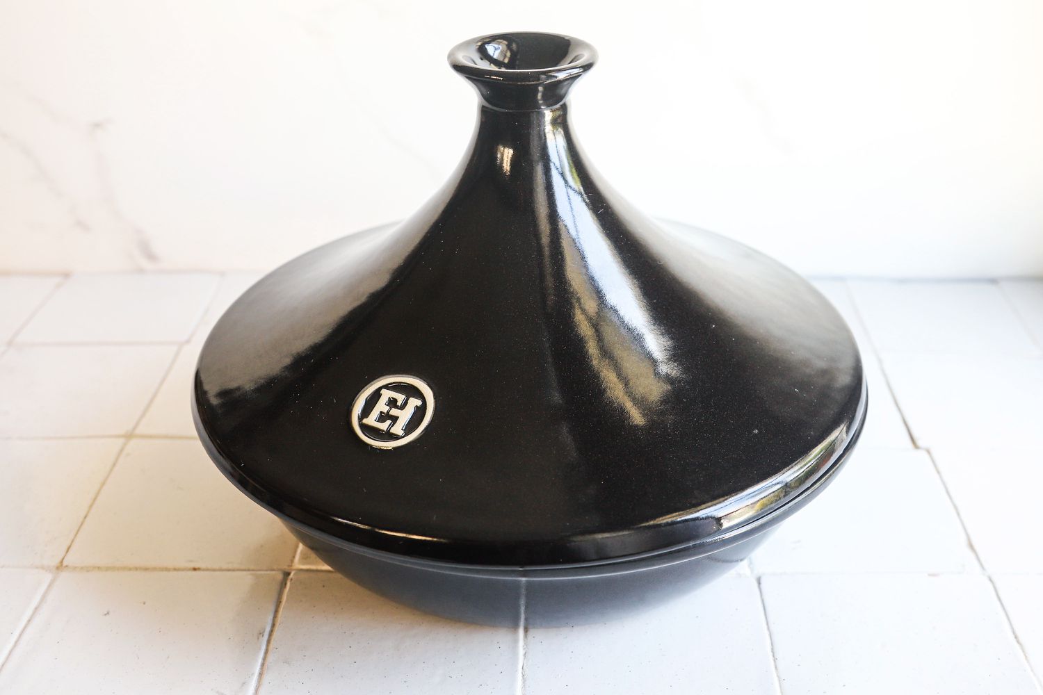 emile henry black tagine on white tile surface