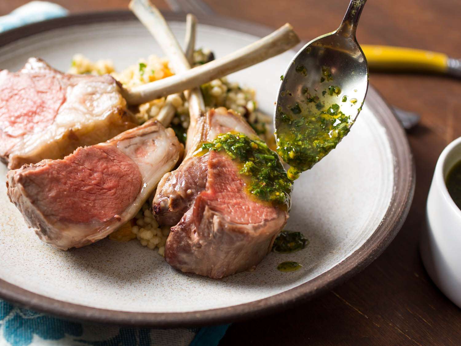 Spooning pistachio-mint sauce over lamb chops from a crown roast of lamb.