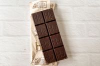  Hu Simple Dark Chocolate on a white brick surface