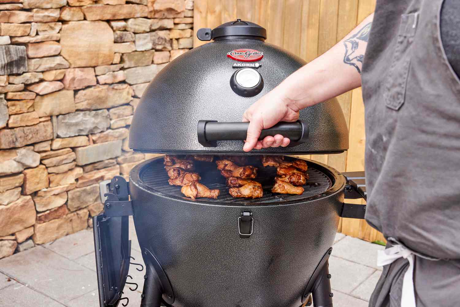 A person closes the top on the Char-Griller E16620 Akorn Kamado Charcoal Grill