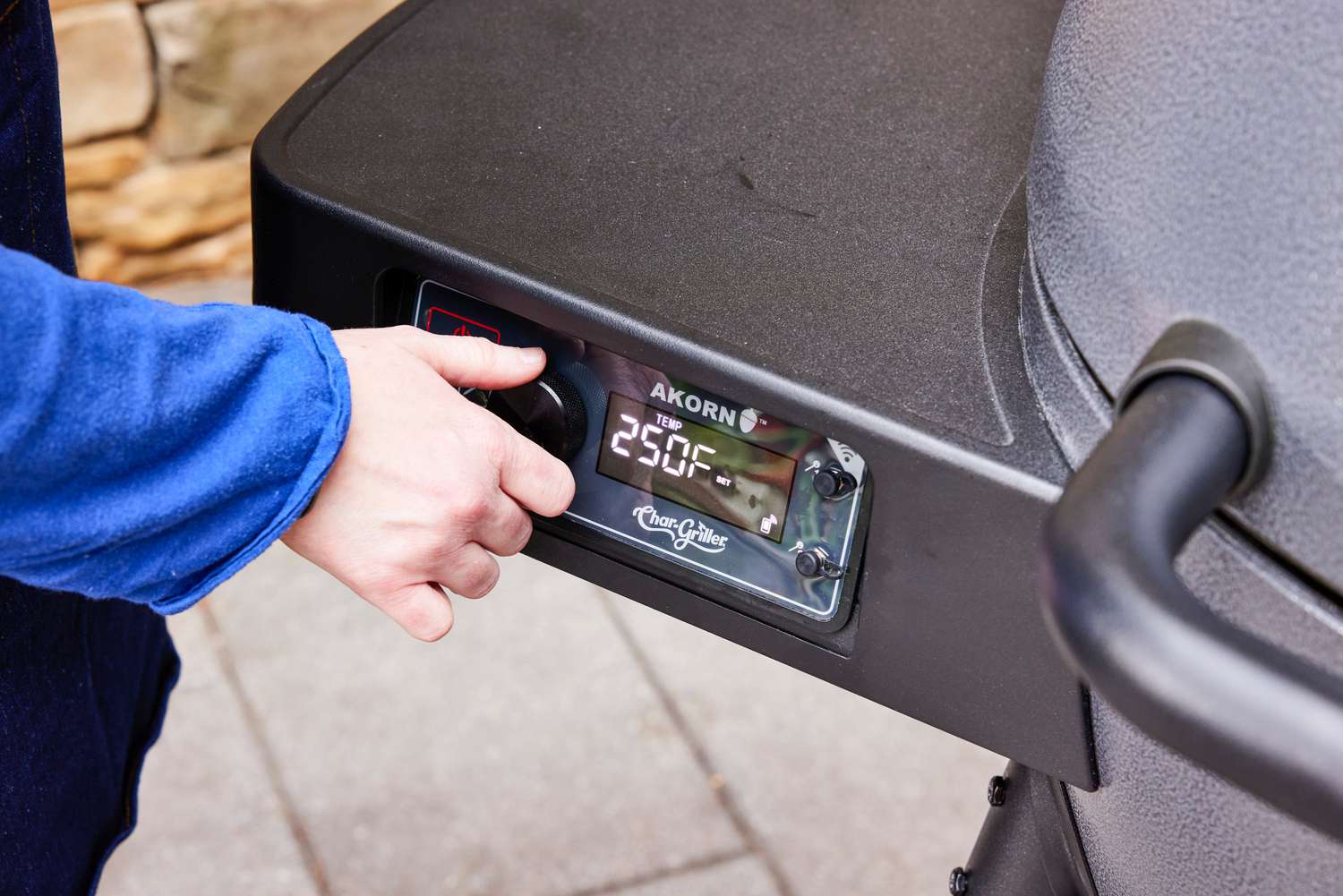 A person adjusts the temperature on the Char-Griller Akorn Auto-Kamado Grill