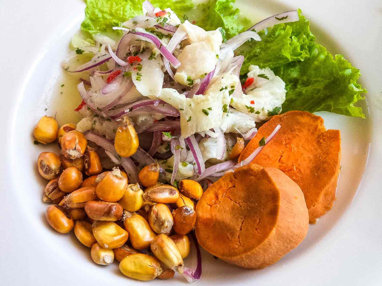 A platter of Peruvian ceviche with boiled corn and sweet potato.
