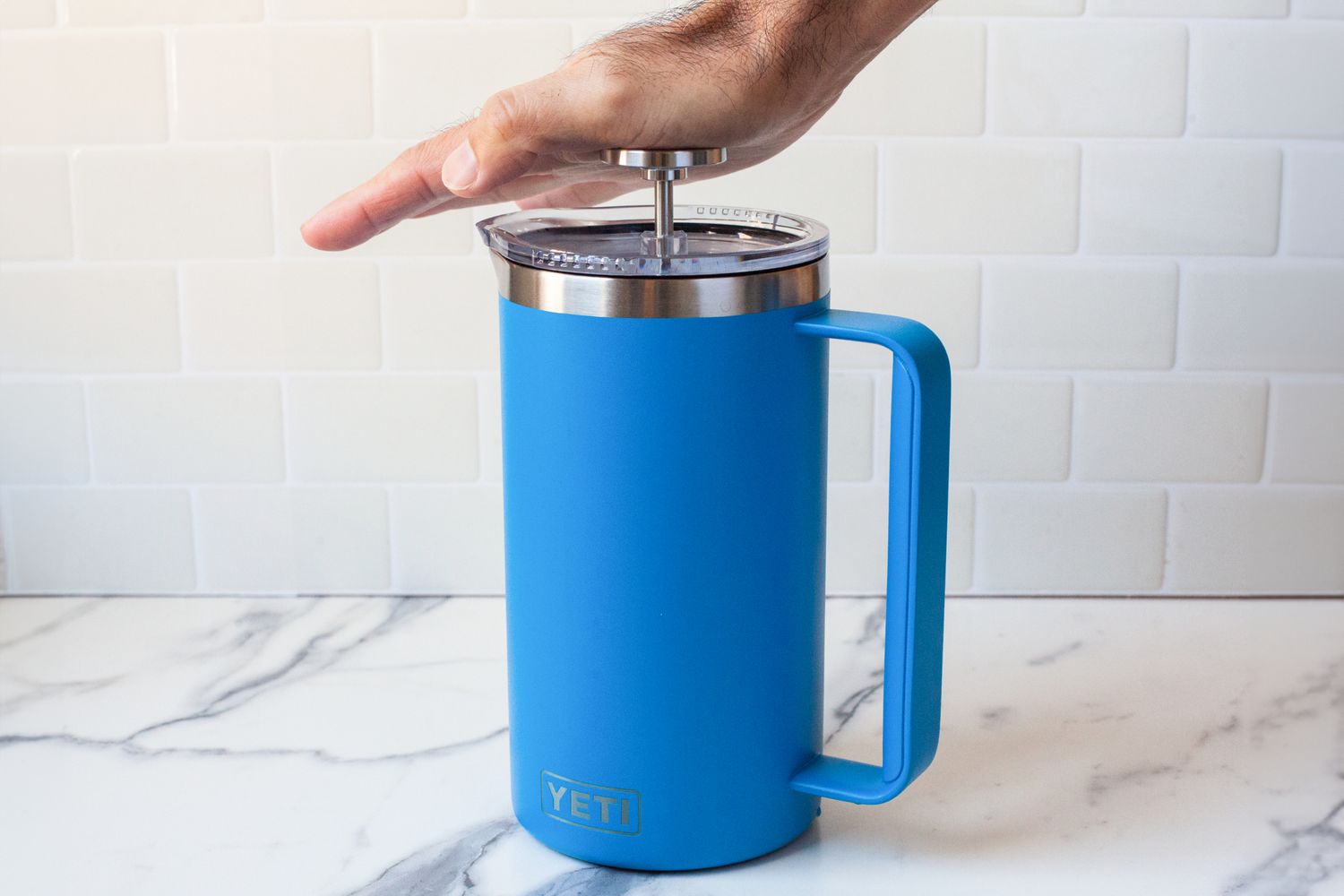 A hand pressing on the top of the Yeti French Press