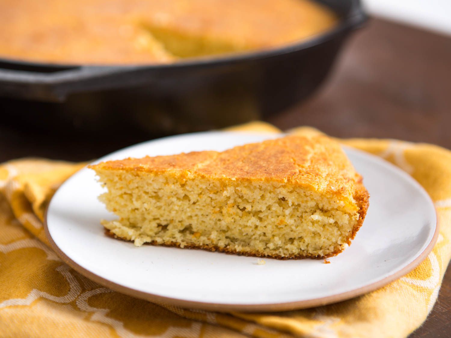 A slice of cornbread on a white plate. 