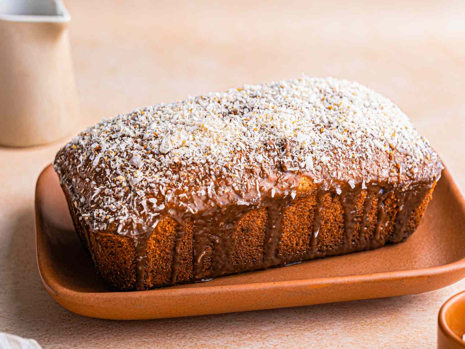 A loaf of banana coconut cake on a platter topped with shredded coconut