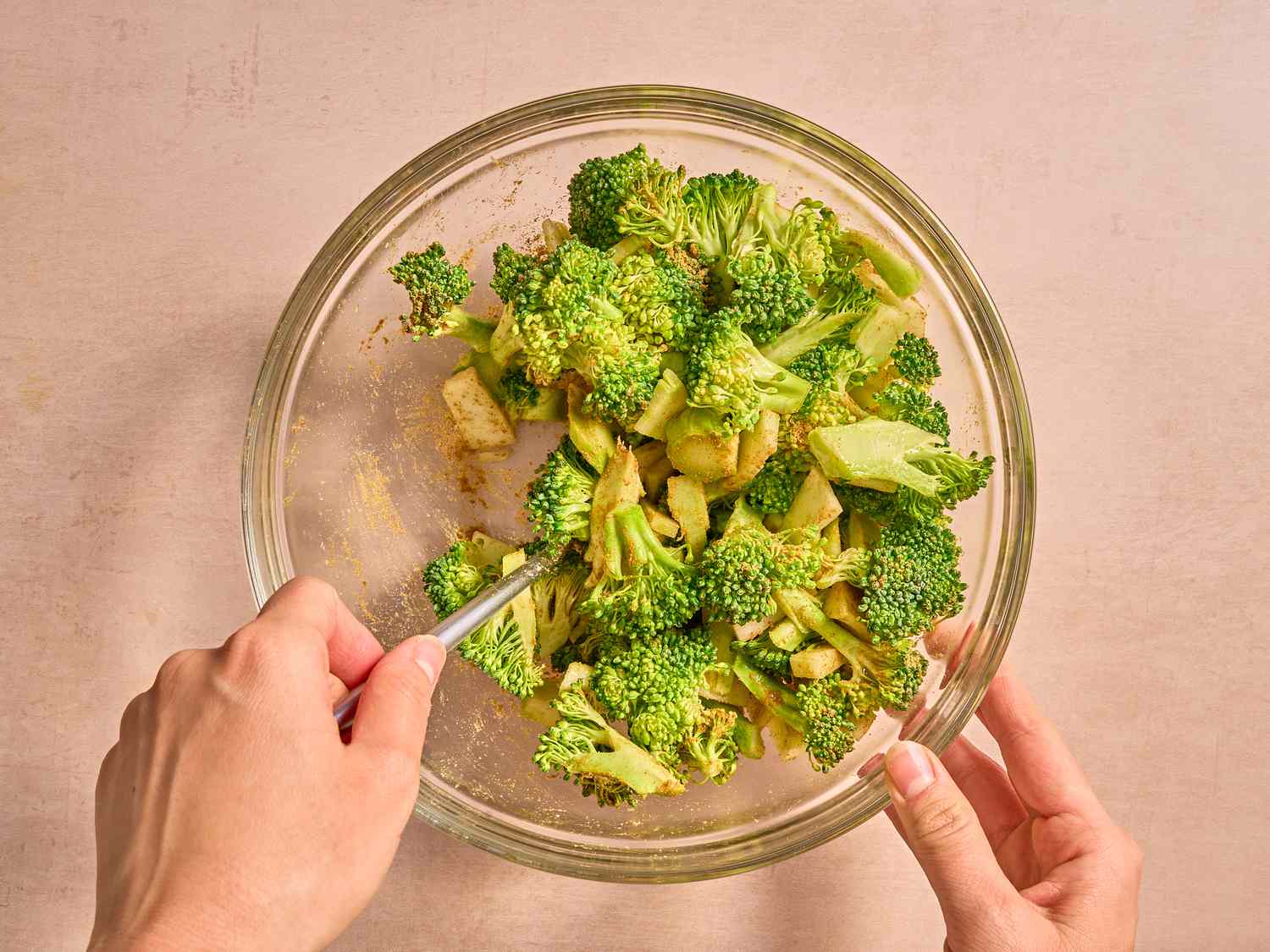 Mixing broccoli with seasoning in a glass bowl 