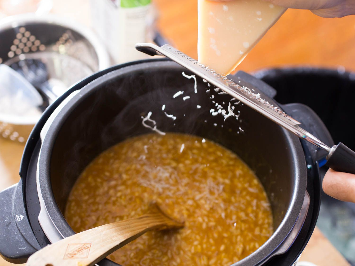 Grating parmesan cheese with a Microplane over risotto rice in a pressure cooker. 