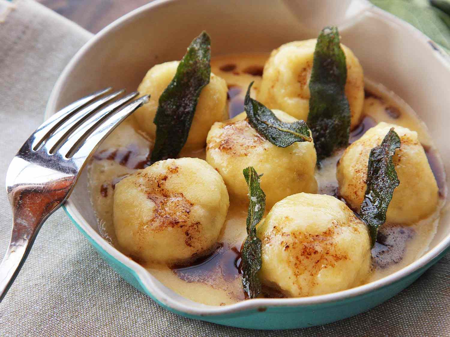 Finished gnudi looking brown and golden in butter sauce, topped with fried sage leaves. 