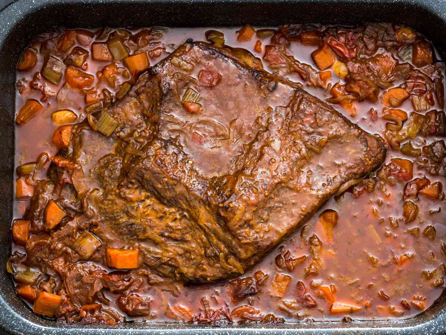 Overhead shot of a Jewish-style braised brisket in a sauce of carrots and onions