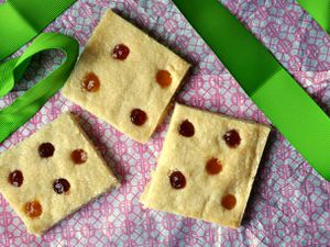 Overhead view of polka dot shortbread cookies arranged on a patterned fabric surface.