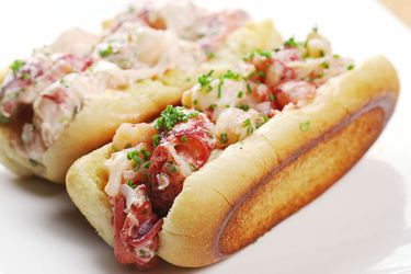 Closeup of two sous vide Connecticut-style lobster rolls, served on a plate.
