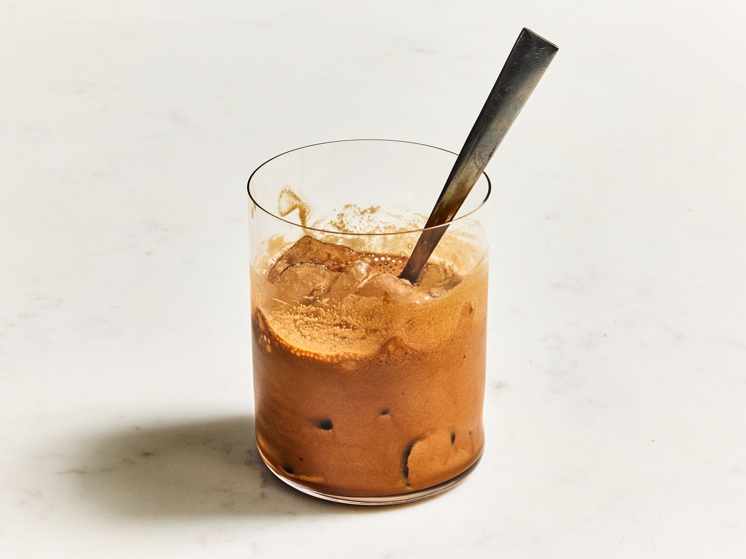 A glass of iced mocha frappe with a spoon standing in it