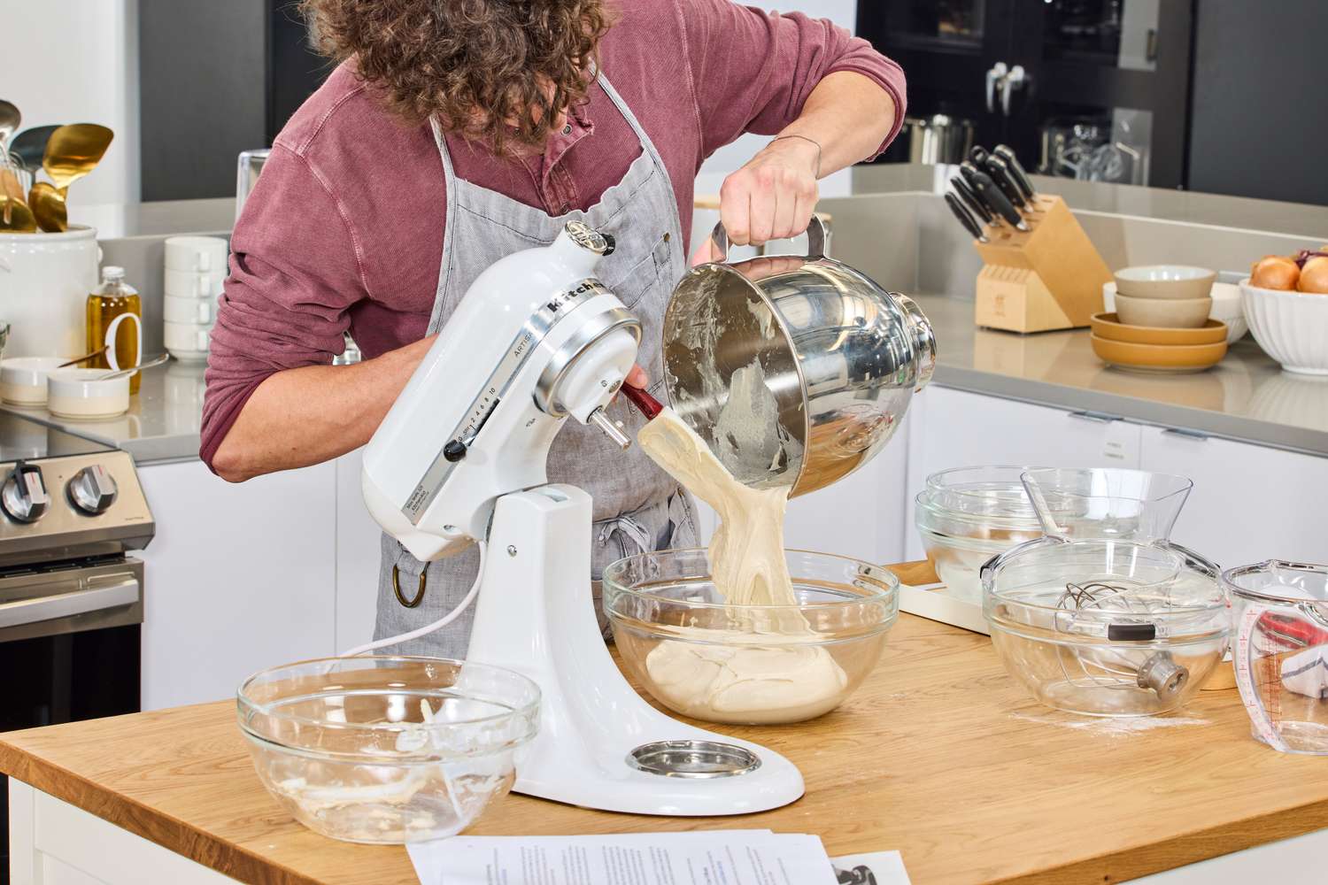 A person pours batter into the KitchenAid 5-Quart KSM150PSER Artisan Stand Mixer
