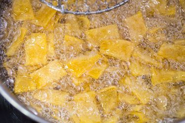 Overhead view of tortilla strips frying in oil.