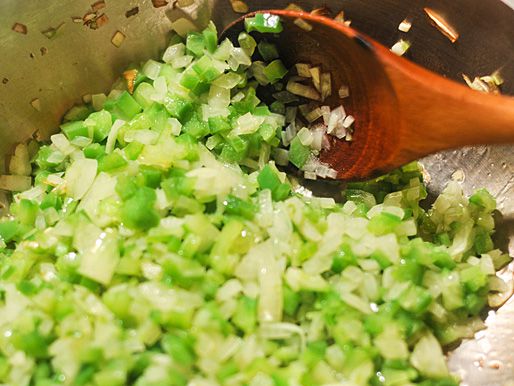 Dice onions, celery, and green peppers being sauted in a saucepan. 