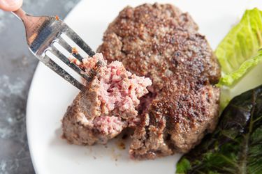 Hache Steak with a bite on a fork on a white plate 