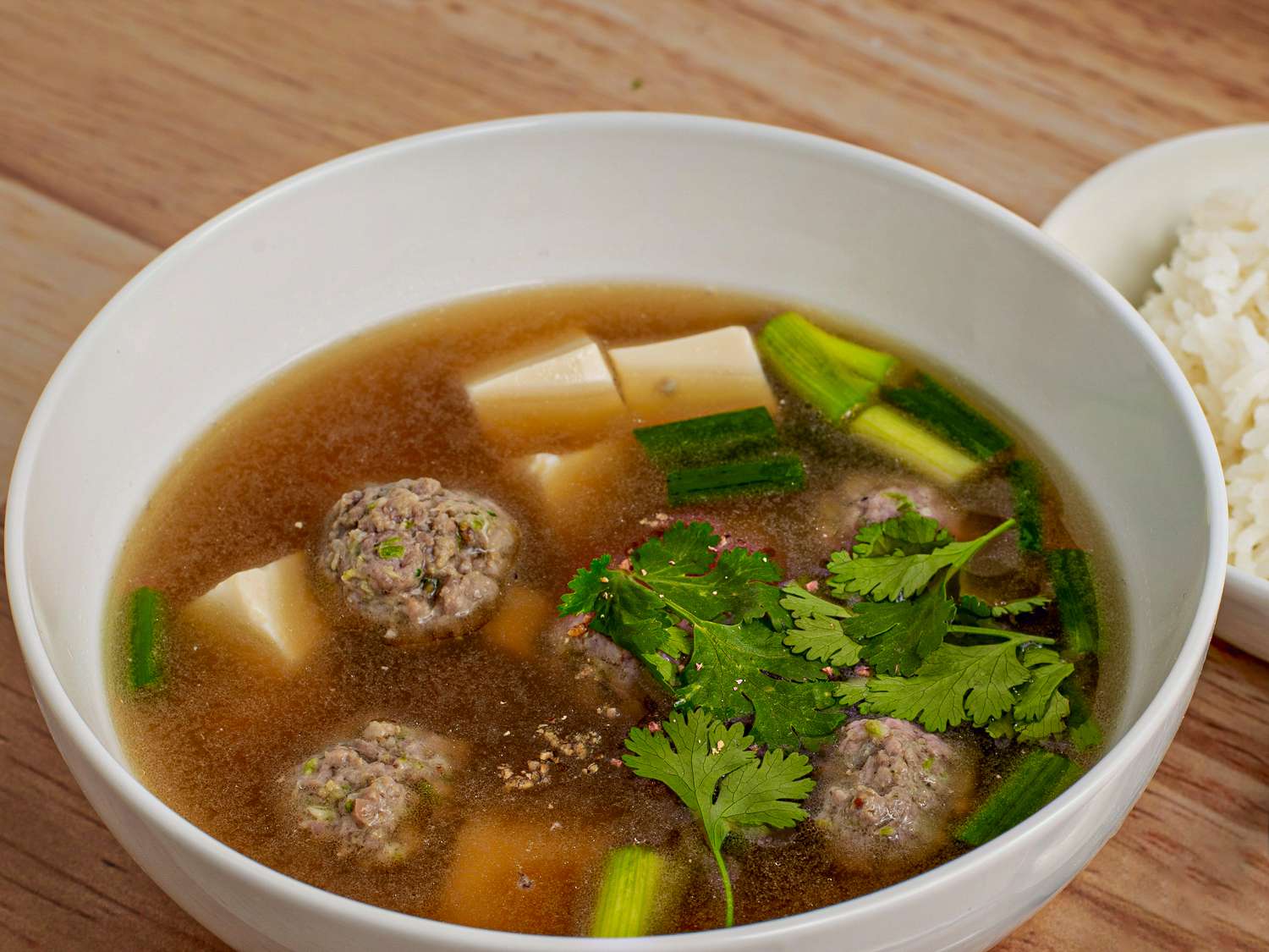 A bowl of soup topped with cilantro leaves.