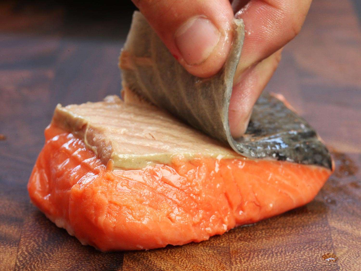Using hands to remove the skin of a salmon fillet cooked sous vide.