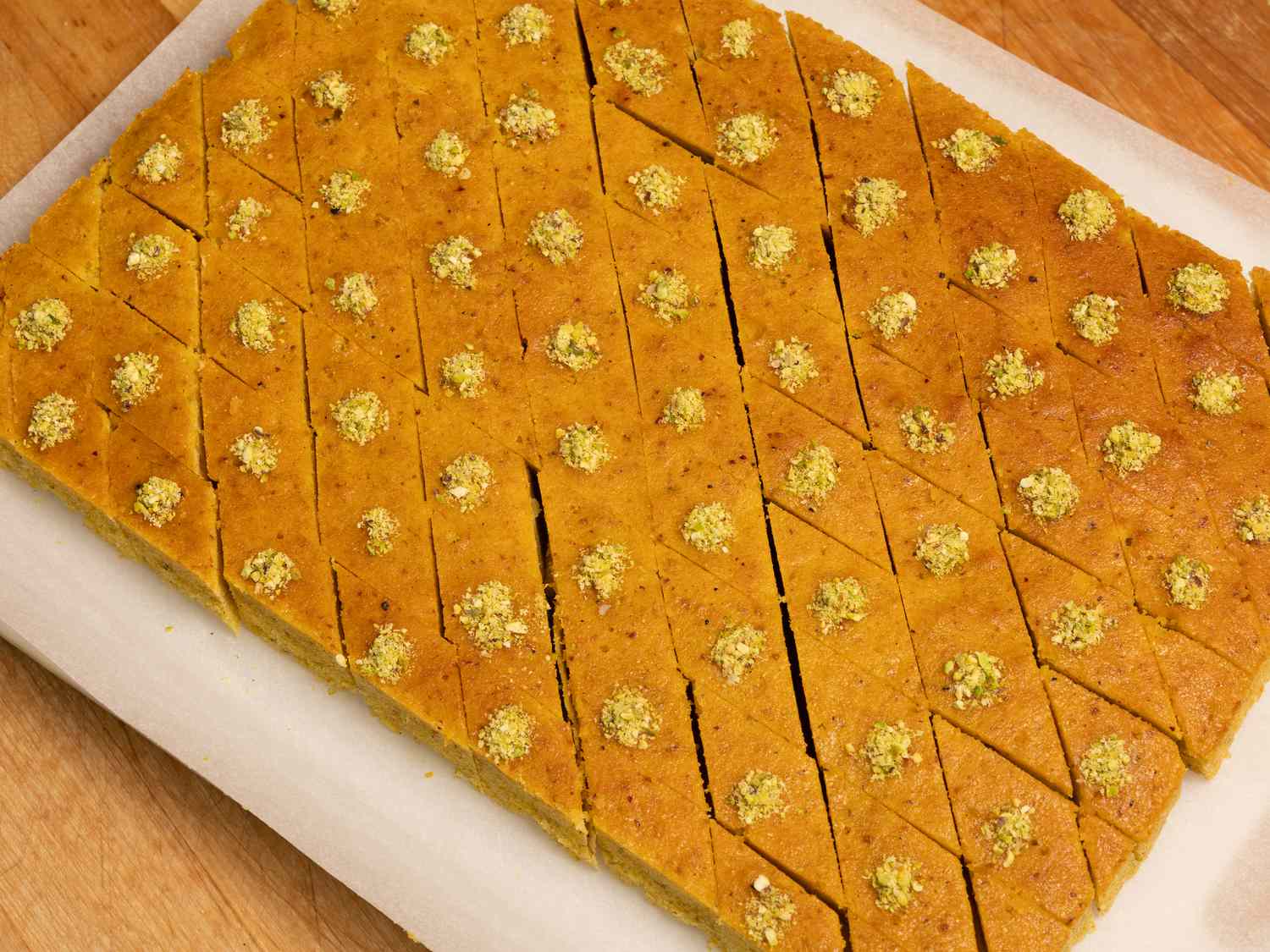 baklava cake cut into squares on parchment paper on a wooden surface 