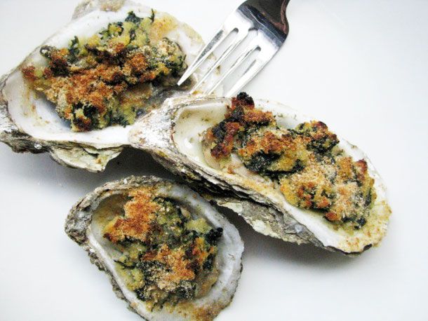Closeup of three Oysters Rockefeller next to a silver fork.