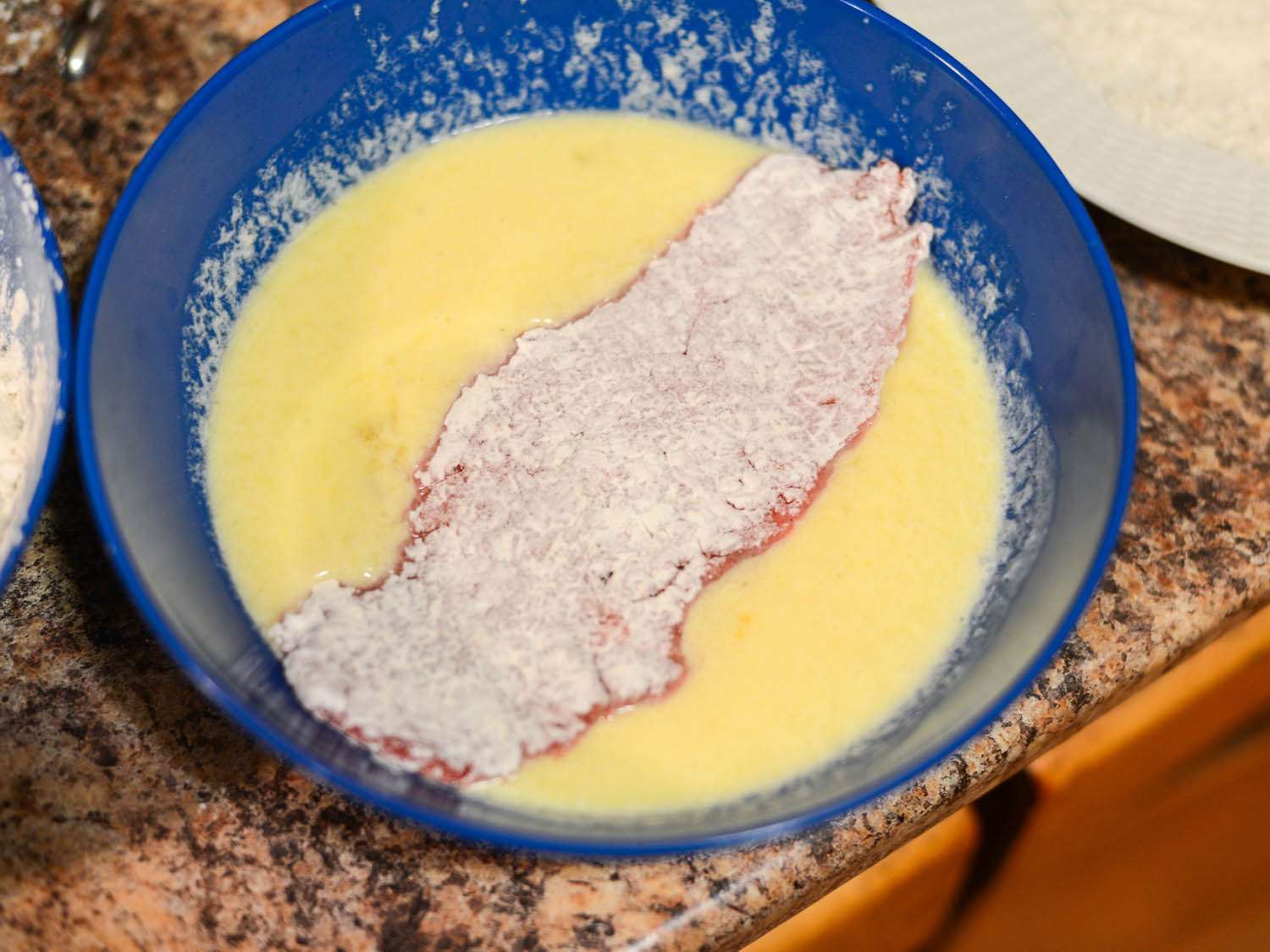 Dipping a floured steak into egg batter.