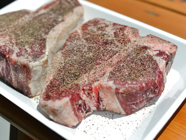 Two porterhouses on a platter, sprinkled with pepper.