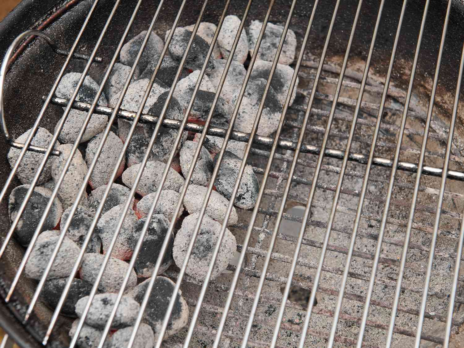 Gray ash covered coal arranged on one side of charcoal grate