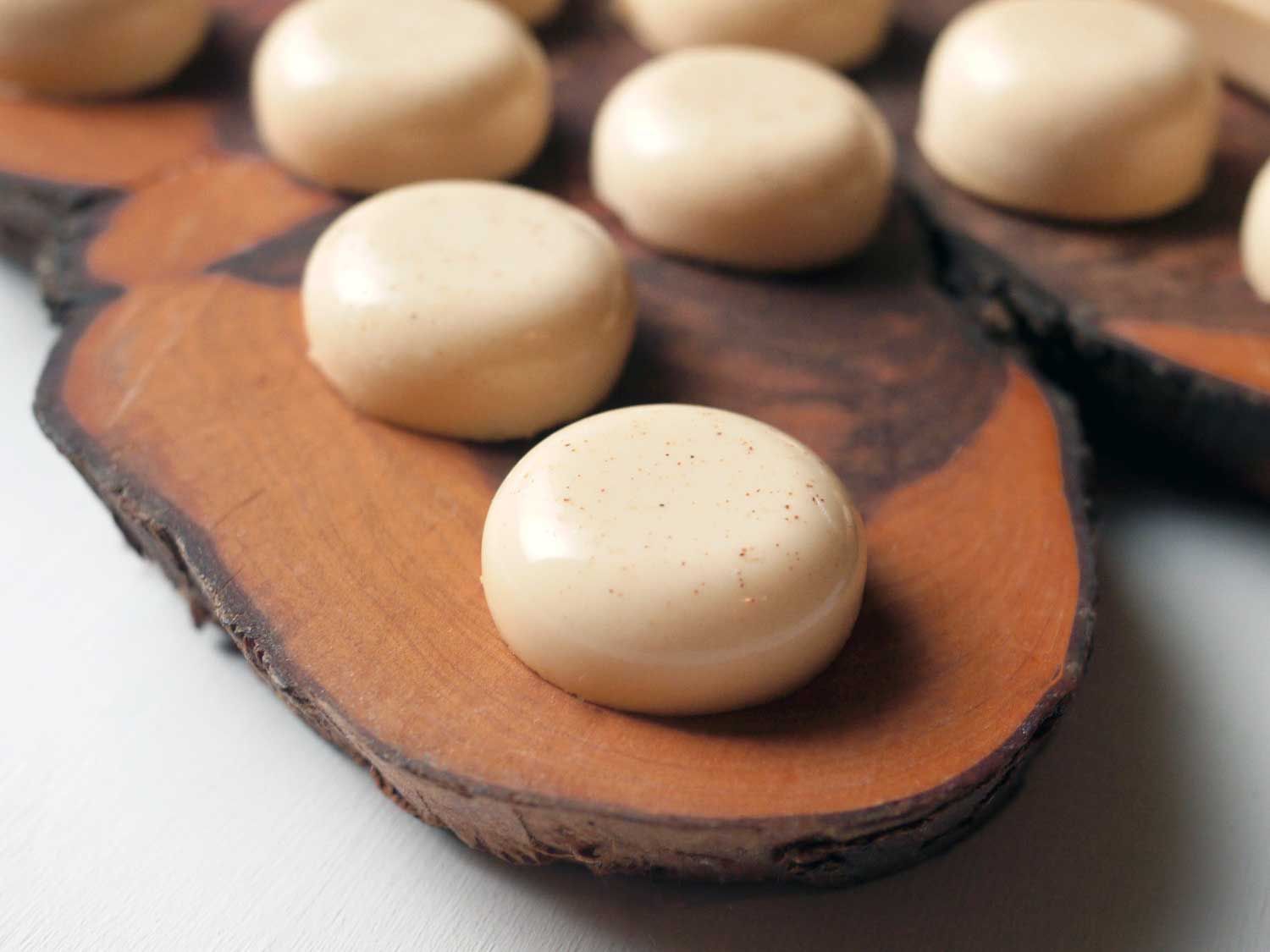 Several eggnog jello shots served on a live-edge platter make of hardwood.