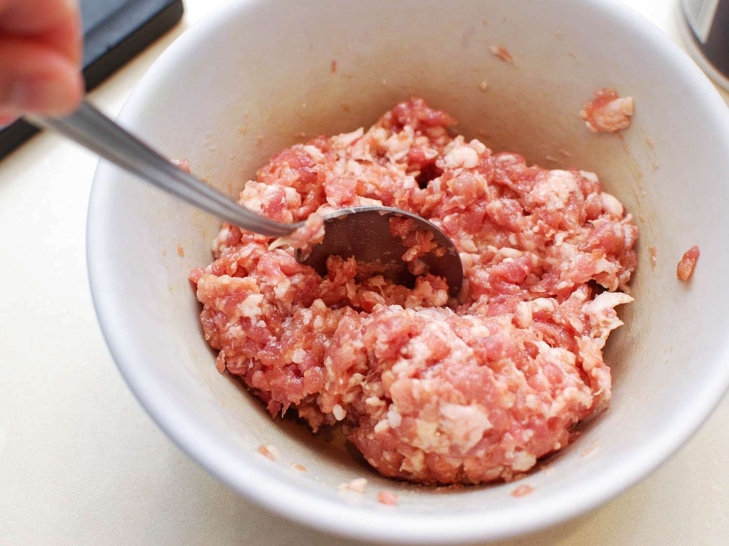 Ground pork being marinated in a mixing bowl. 