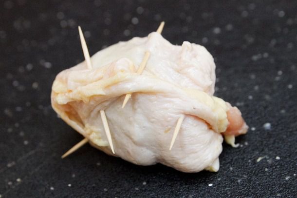 A matzo ball with a wrapping of raw chicken skin, held in place with toothpicks
