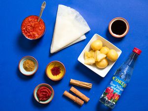 A collection of ingredients used in Moroccan cooking, including preserved lemon, rose water, cinnamon, saffron, Ras el Hanout, harissa, and a sheet of warqa pastry 