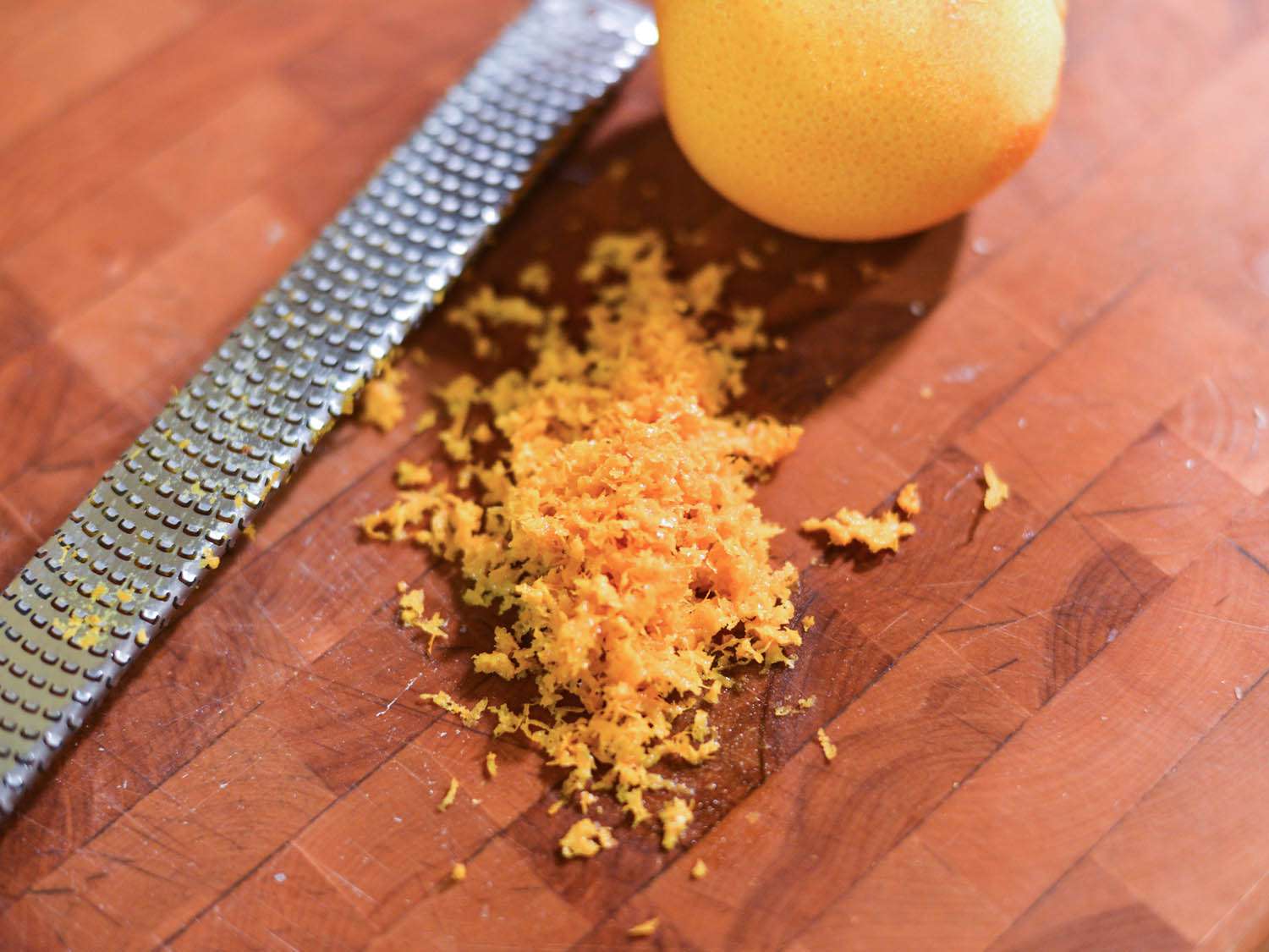 A pile of microplaned orange zest on a cutting board.