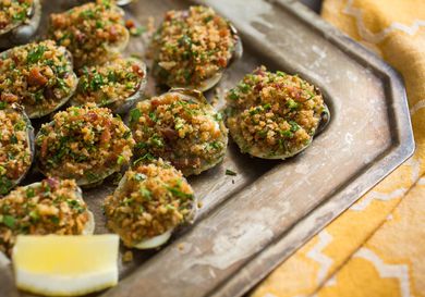 A tray of easy, ultimate Clams Casino with a lemon wedge. 
