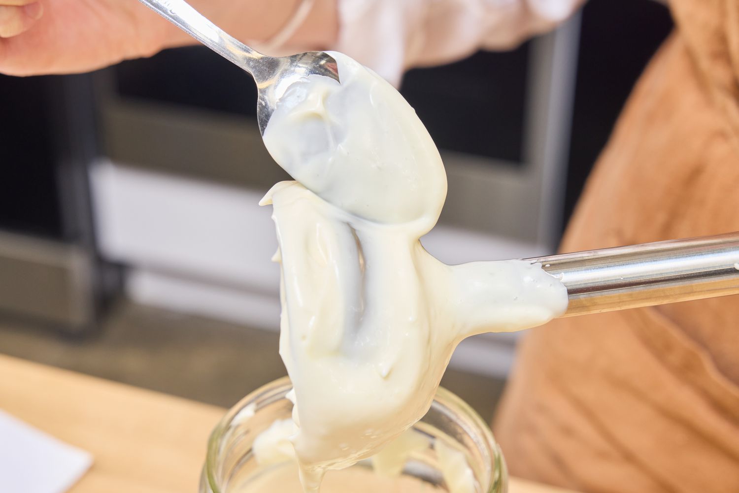 A person spoons puree from the blade of the Hamilton Beach 2-Speed Hand Blender