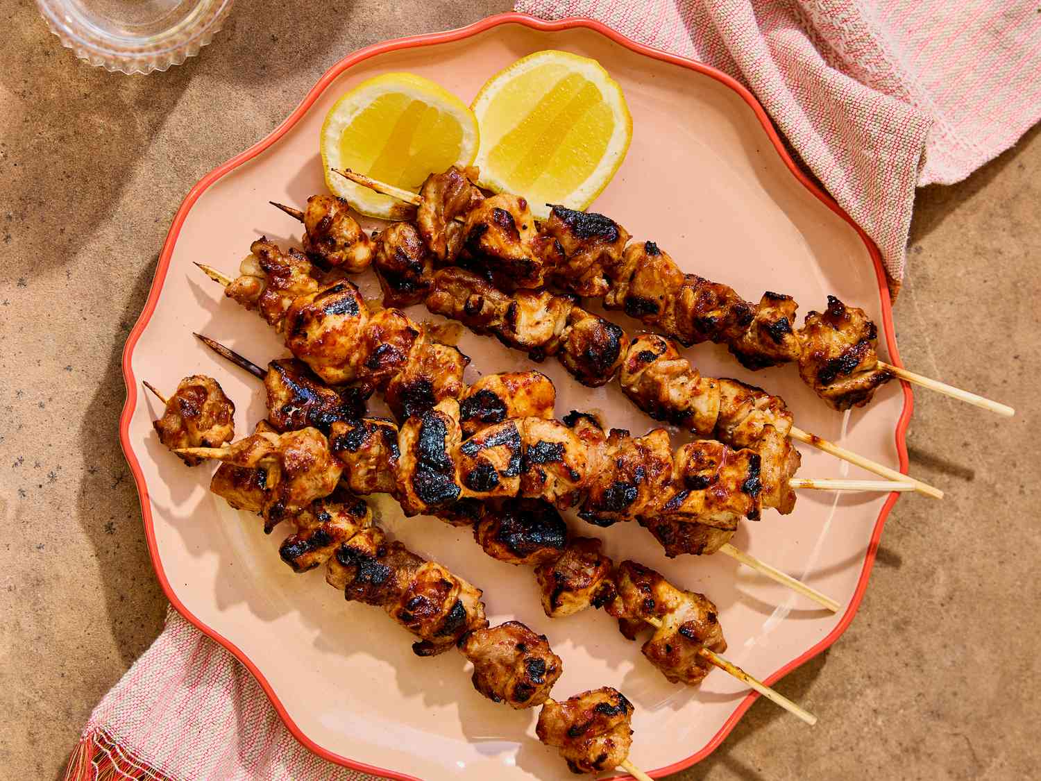 Honey harissa glazed chicken skewers on a platter with lemon slices