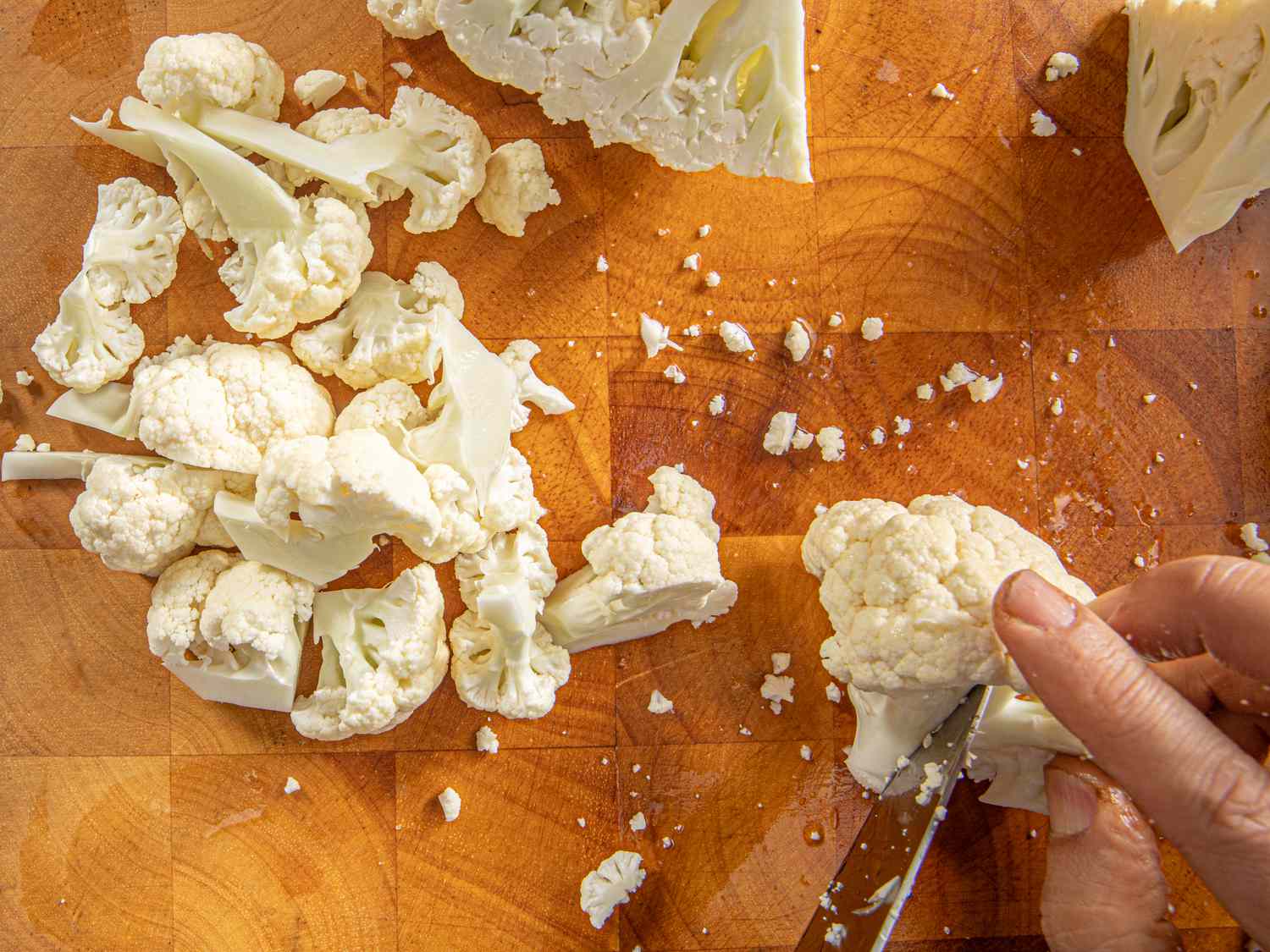 Overhead view of cutting cauliflower florets into smaller pieces