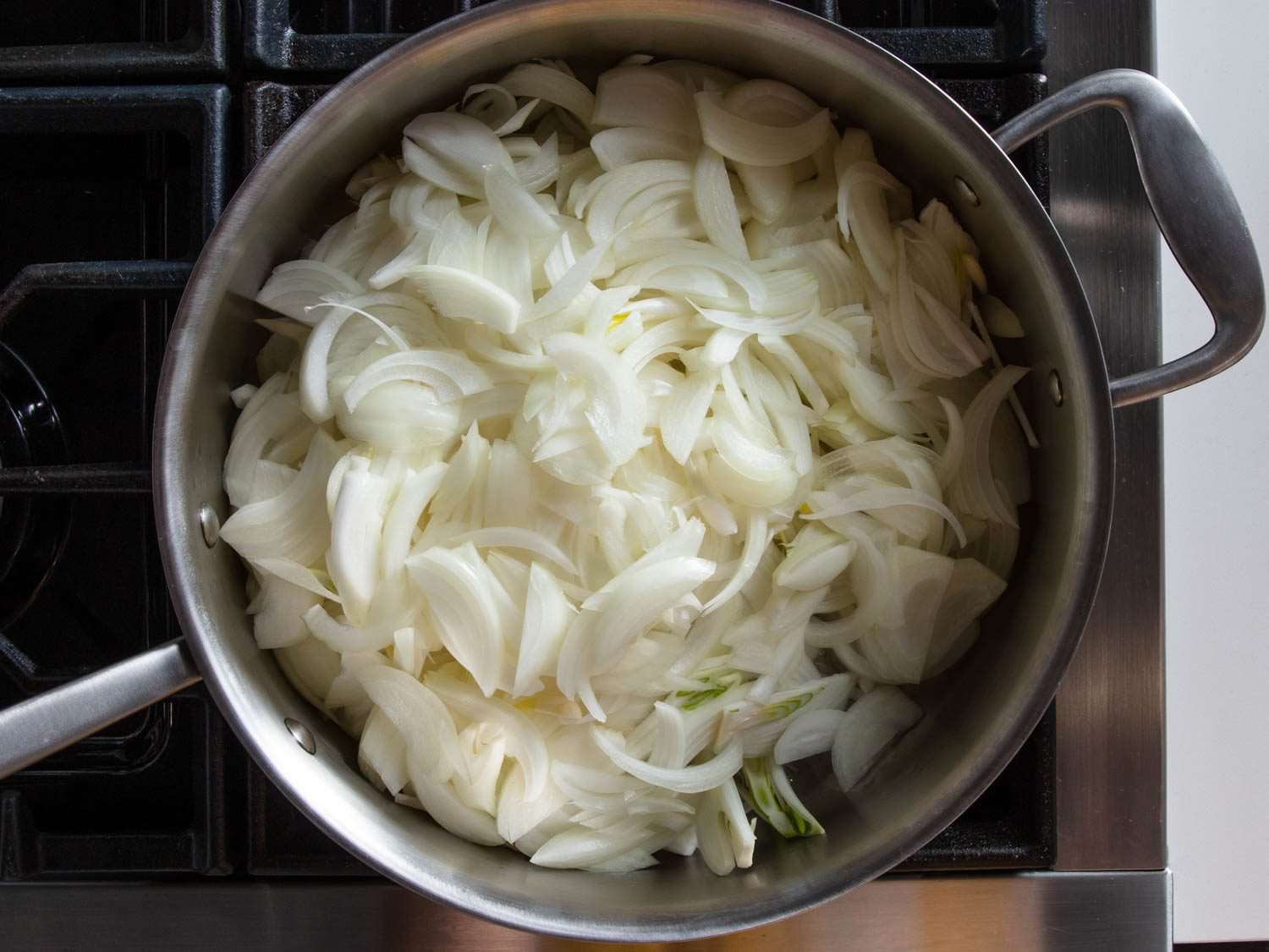 Uncooked sliced onions in a pan.