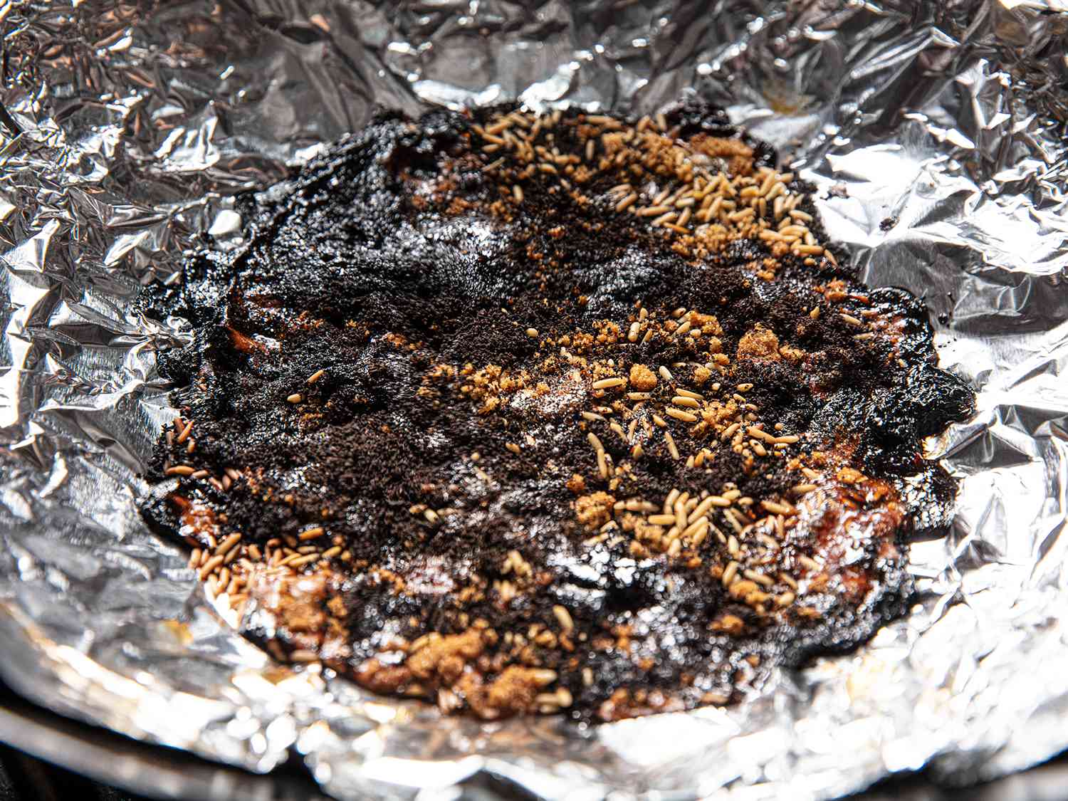 A close of view of smoking materials, partially combusted, in a tin foil-lined wok.