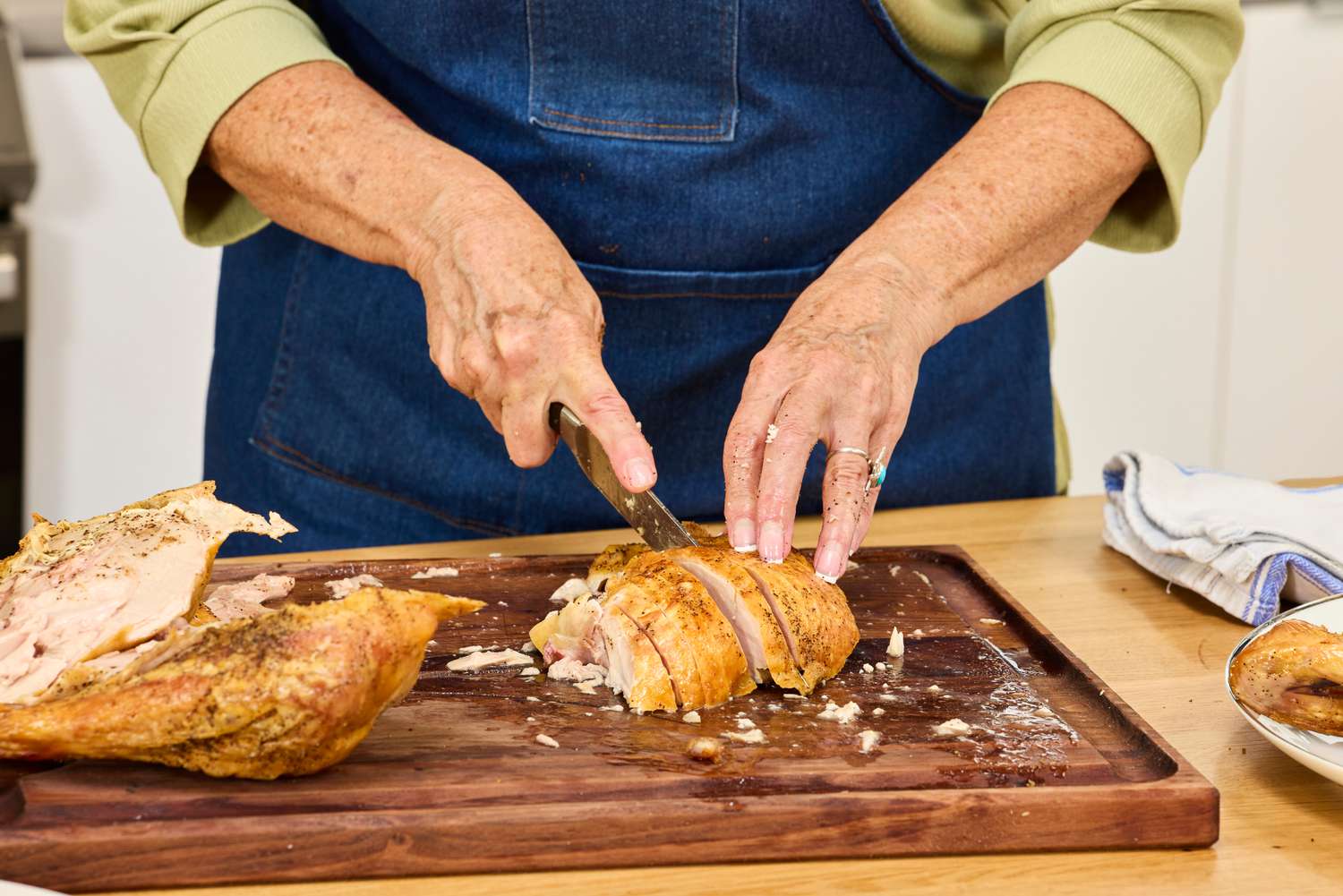 A person cutting up breast meat from a Williams Sonoma Willie Bird Turkey