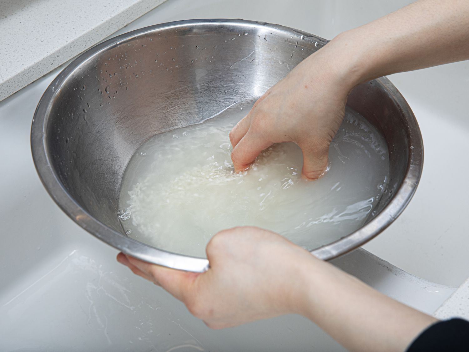 Side view of swishing rice in a bowl of water
