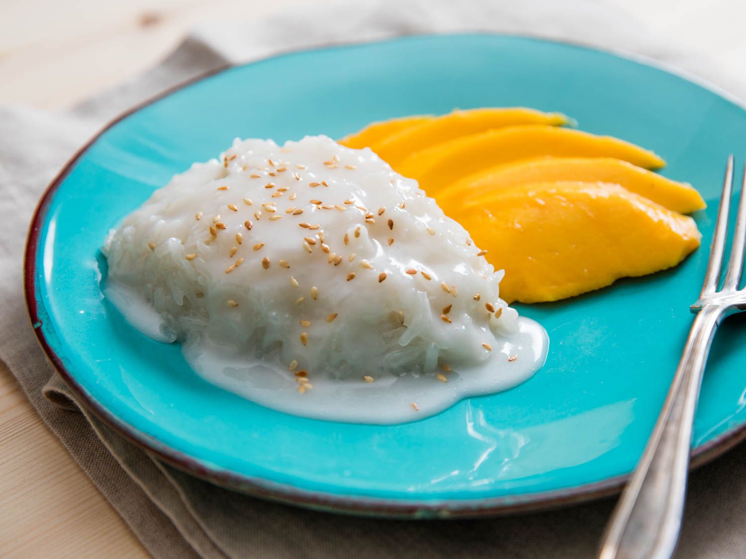 Thai coconut sticky rice with mango on a blue plate.