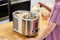 A person pouring liquid into the Lello Musso Lussino 4080 Ice Cream Maker