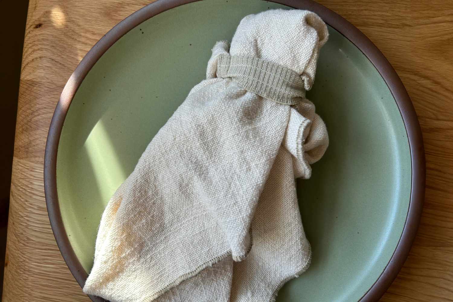 A cloth napkin on a green plate in the sunlight