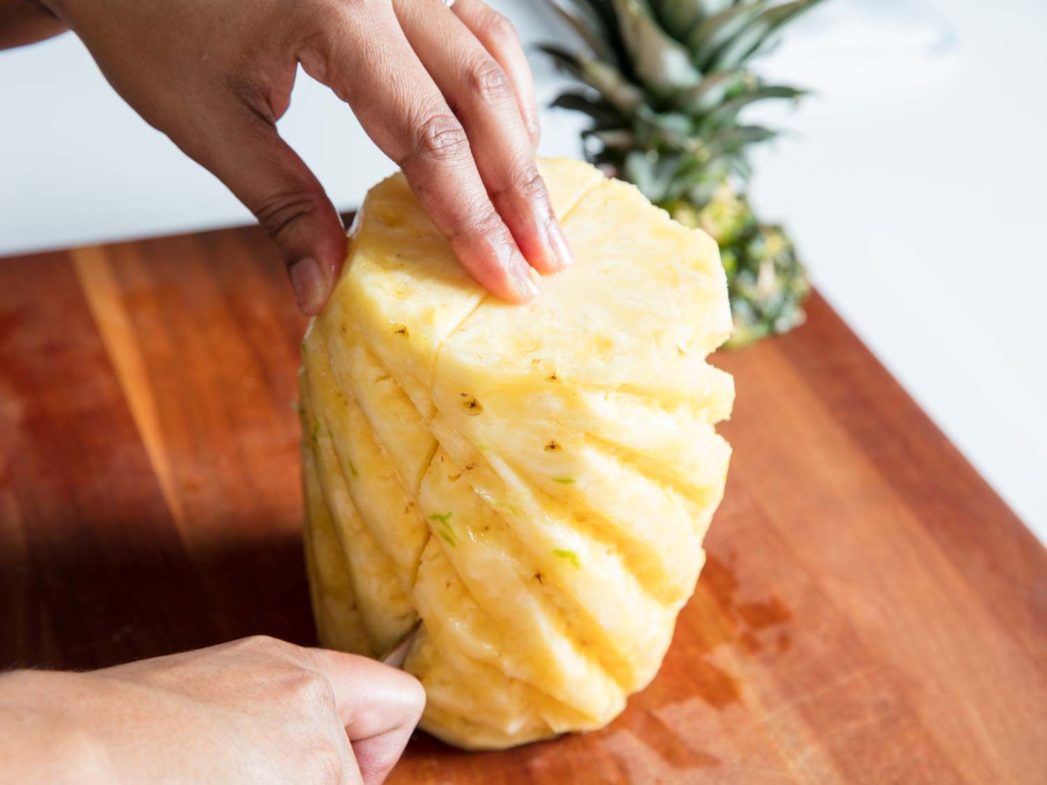 A knife slicing a pineapple in half.