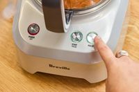 A person presses the 'PULSE' button on the Breville BFP660SIL Sous Chef 12-Cup Food Processor
