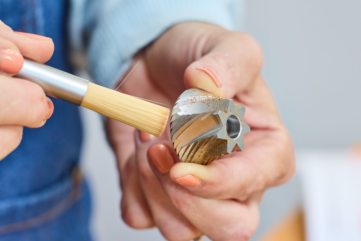 A person cleans a piece from the Comandante C40 Nitro Blade Grinder with a small brush