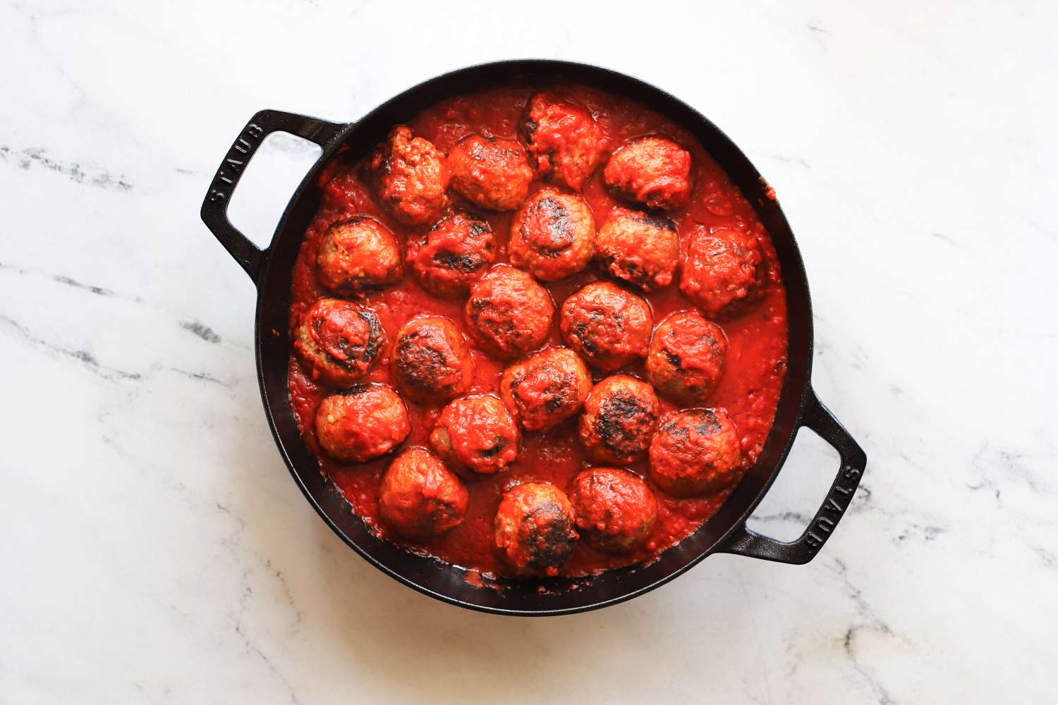 Cooked meatballs in a cast iron skillet with tomato sauce