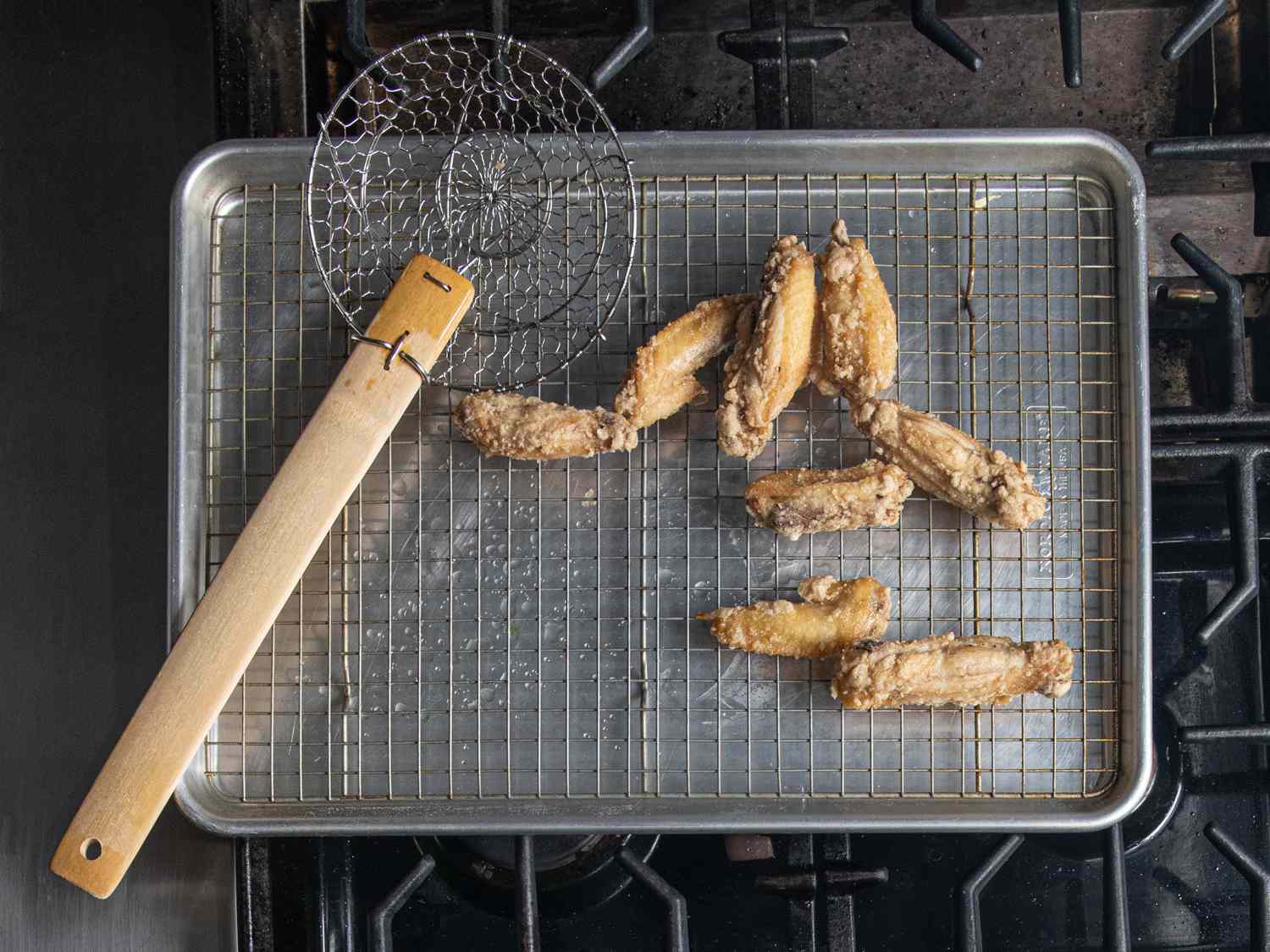 A metal spider resting next to deep fried chicken wings