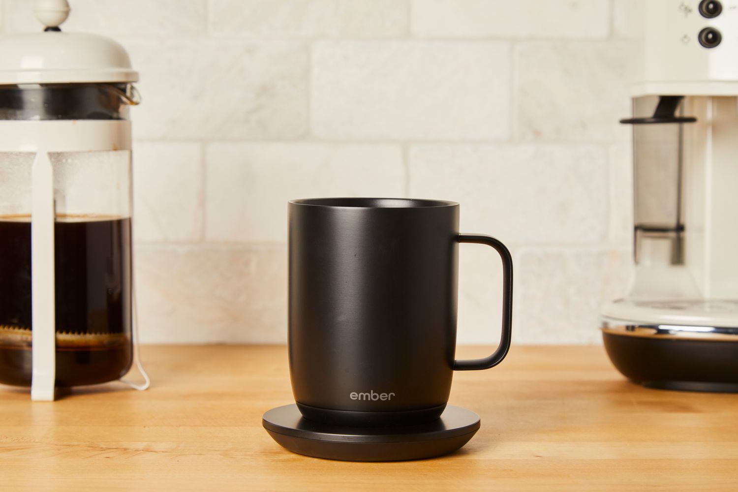 The Ember mug surrounded by coffee making equpiment on a wooden surface